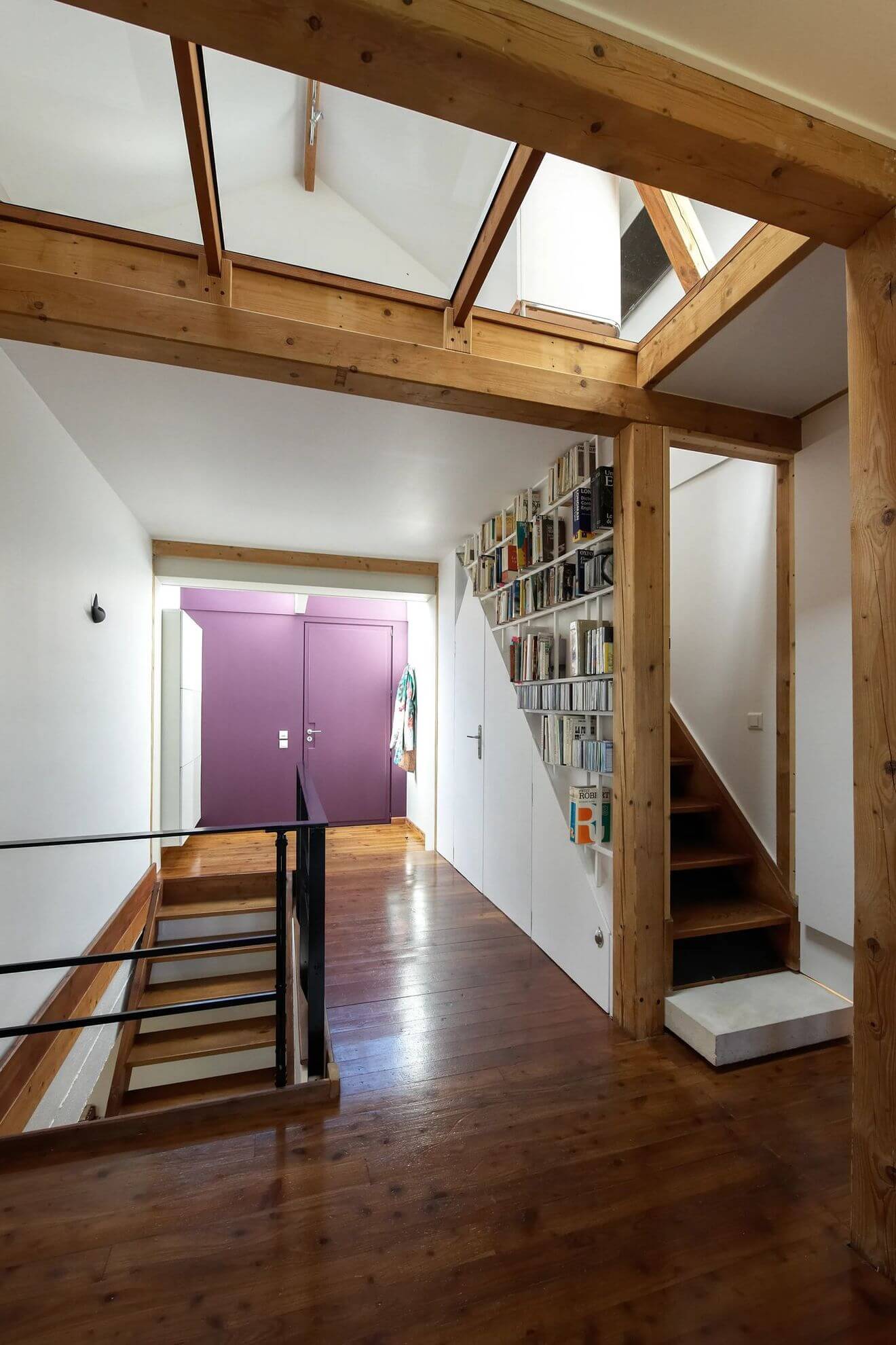 13- In the hallway, the bookcase follows the shape of the stairs